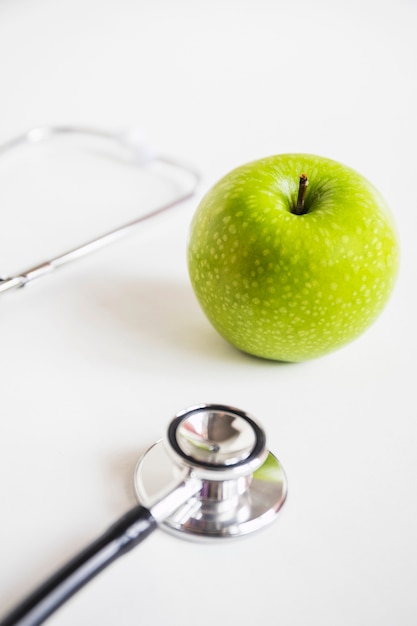 Free photo green apple and stethoscope on white background