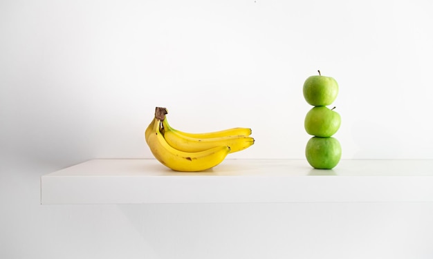 Green apples and bananas on a white background closeup