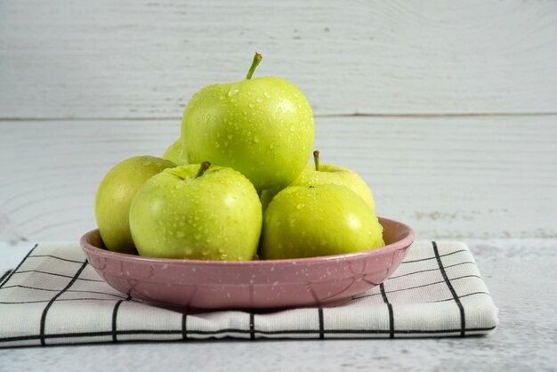 Green apples in a ceramic saucer on the towel