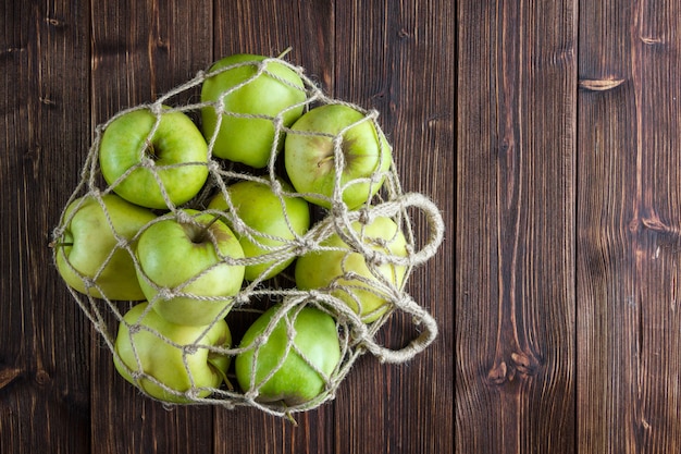 Free photo green apples in a net bag top view on a wooden background free space for your text