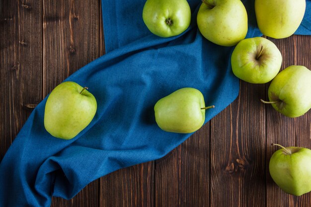 Free photo green apples top view on a blue cloth and wooden background