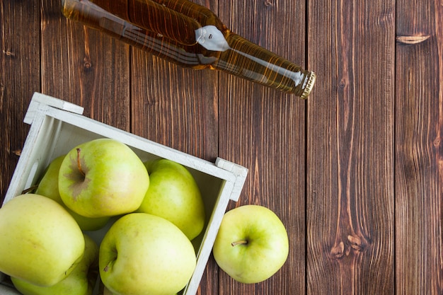 Free Photo green apples in a wooden box with apple juice flat lay and wooden background space for text