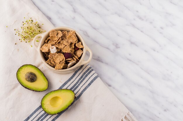 Green avocado with cereal in bowl on table 