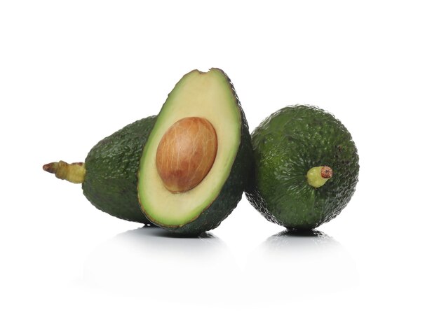 Green avocados on a white surface