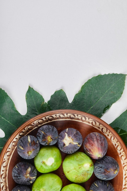 Free photo green and black figs on a ceramic plate and on a white background. high quality photo