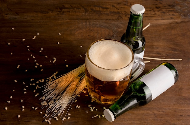 Free photo green bottles of beer with glass of beer on wooden table