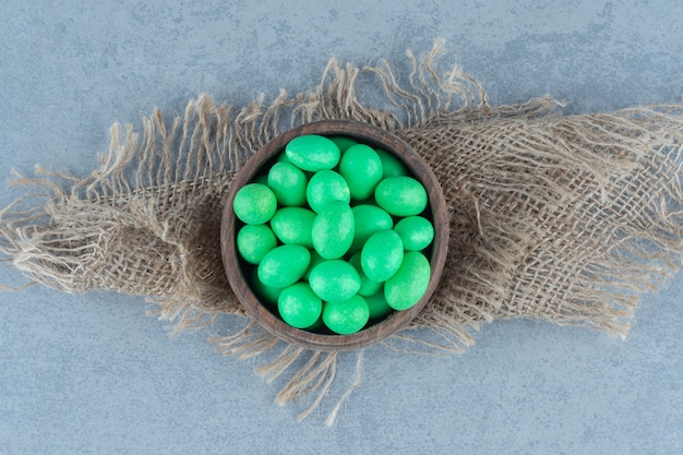 Green candies in the cup on the trivet, on the marble table. 