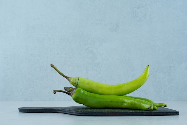 Green chili peppers on dark board.