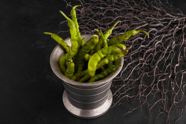 Green chili peppers in a metallic pot. 