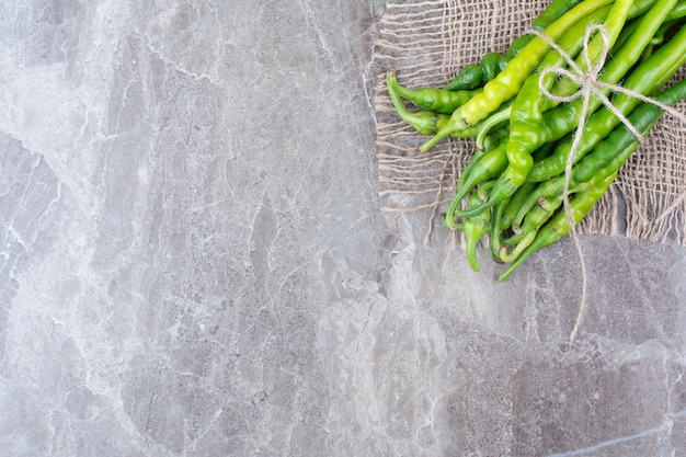 Free photo green chili peppers tied with rope on burlap.