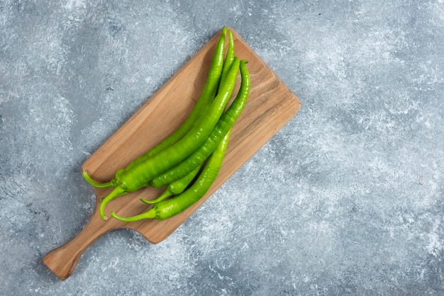 Green chili peppers on wooden board.