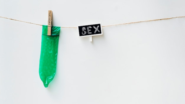 Green condom on clothesline with white background