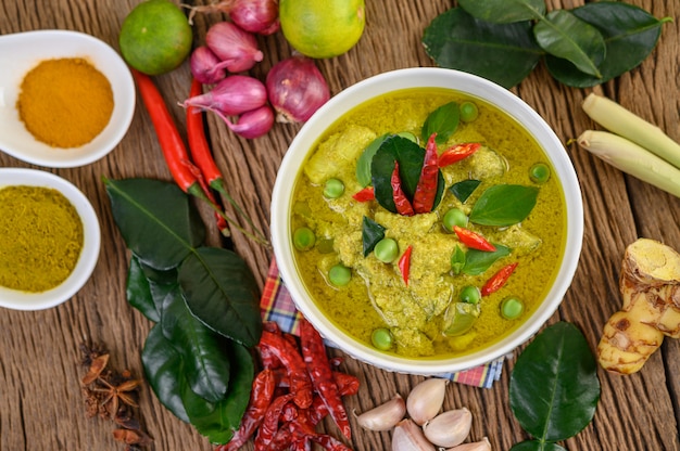 Free Photo green curry in a bowl and spices on wooden table.