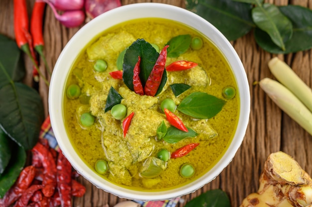 Green curry in a bowl with lime, red onion, lemon grass, garlic and kaffir lime leaves