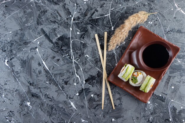 Green dragon sushi rolls placed on brown plate with soy sauce. 