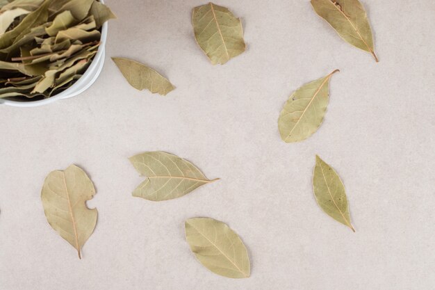 Green dried bay leaves in a ceramic bowl.