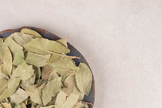 Green dried bay leaves on a wooden platter.