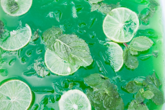 Free photo green drink with sliced lime and mint with iced, close up