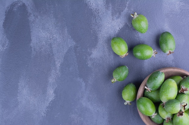 Free photo green feijoas in a mini cup on blue.