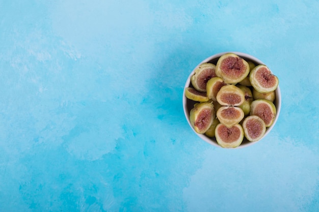 Green figs with red seeds in a white ceramic bowl ,  top view