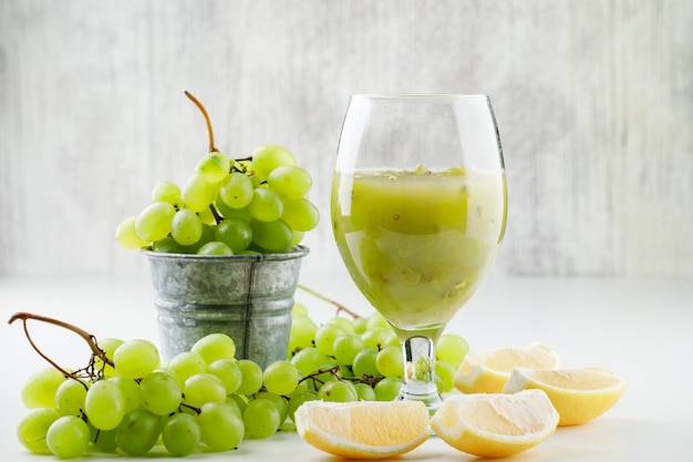 Free photo green grapes with lemon slices, grape cocktail in a mini bucket on white surface