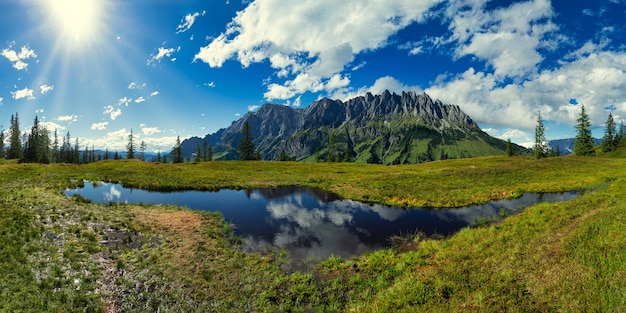 Free Photo green grass field near lake under blue sky and white clouds during daytime