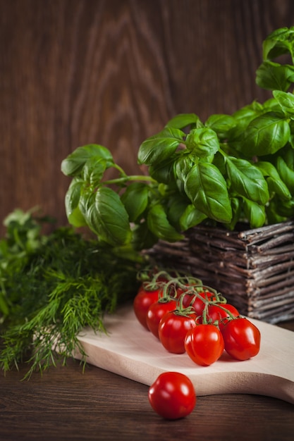 Free photo green herb and twig of cherry tomatoes on wood