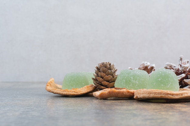 Green marmalade with dried fruits and pinecones on marble background. High quality photo