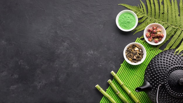 Free photo green matcha tea powder and bamboo stick with copy space black background