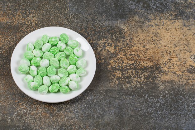 Green menthol candies on white plate. 