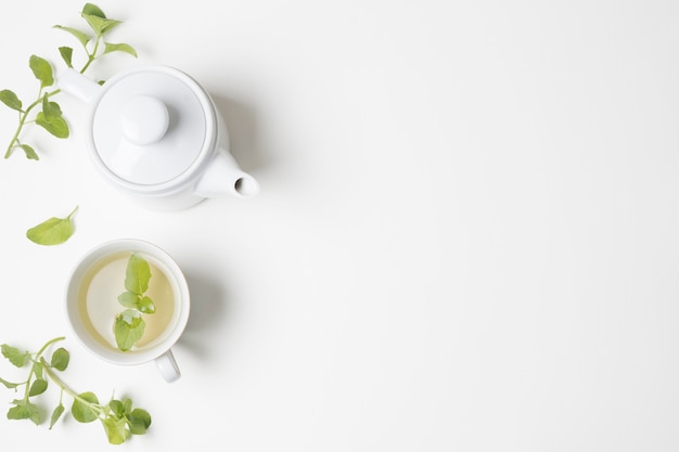 Green mint leaves and tea cup with teapot isolated on white backdrop