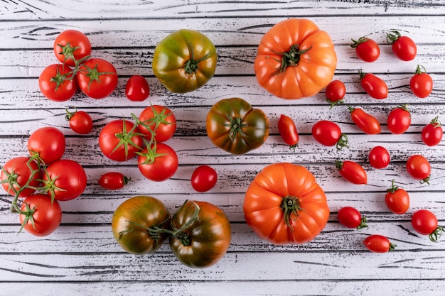 green orange tomatoes and branches of cherry tomatoes on white wooden