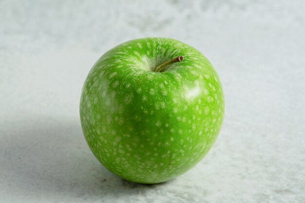 A green organic fresh apple. On grey surface. 