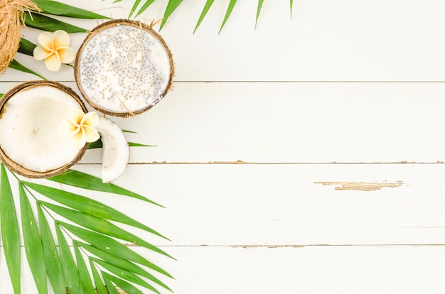 Free photo green palm leaves with coconuts on wooden table