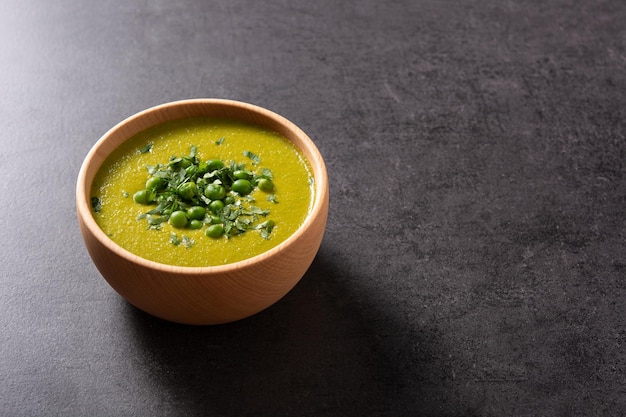 Green pea soup in a bowl on black slate background