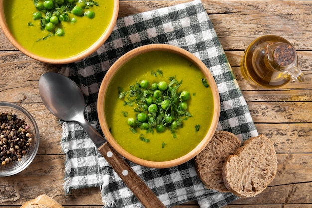 Free photo green pea soup in a bowl on rustic wooden table top view