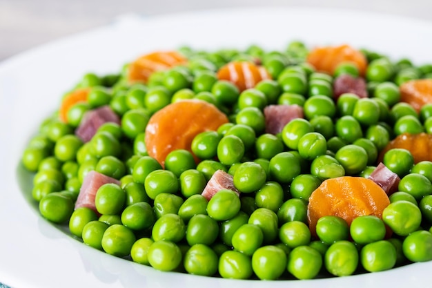 Free Photo green peas with serrano ham and carrot on wooden table