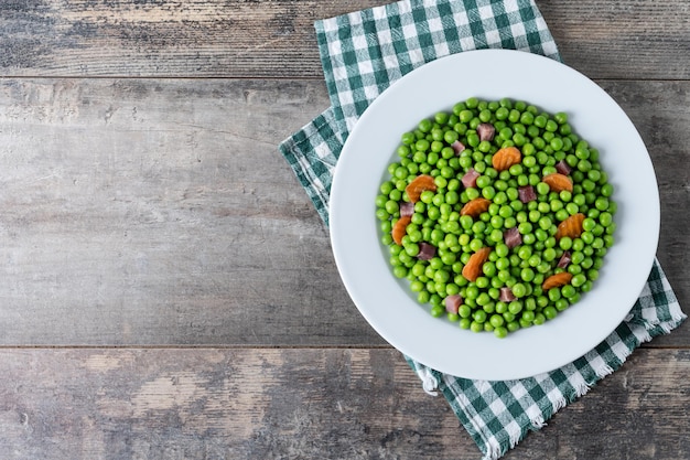 Free Photo green peas with serrano ham and carrot on wooden table