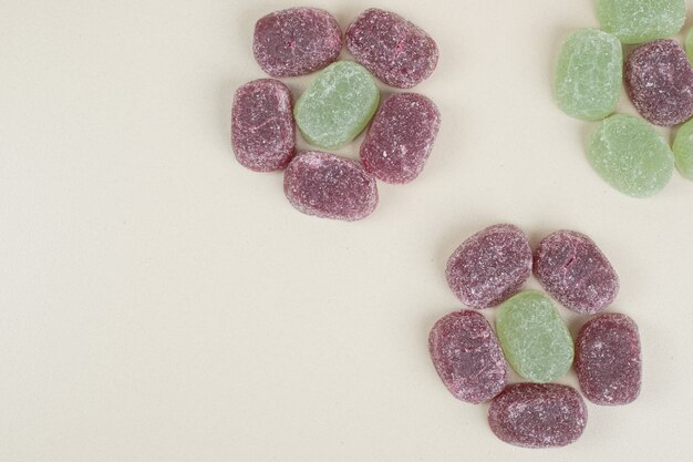 Green and purple jelly candies on beige surface