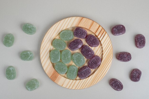 Green and purple jelly candies on wooden plates