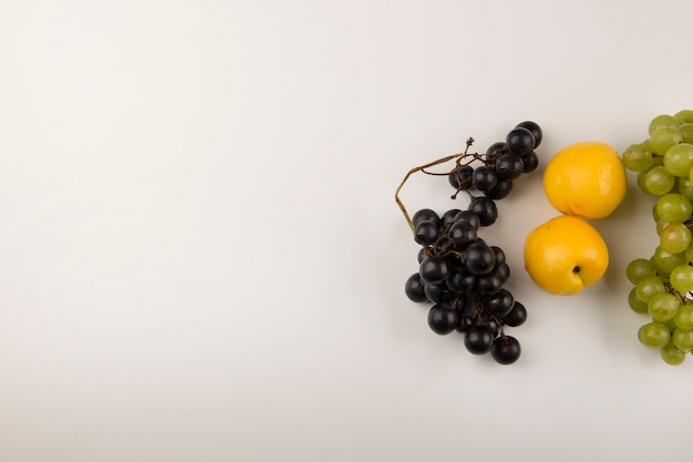 Green and red grape bunches with yellow peaches in the right side