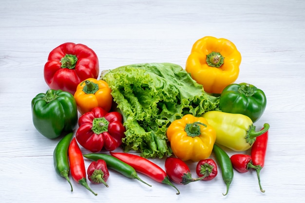 green salad along withful bell peppers and spicy peppers on light desk, vegetable food meal ingredient