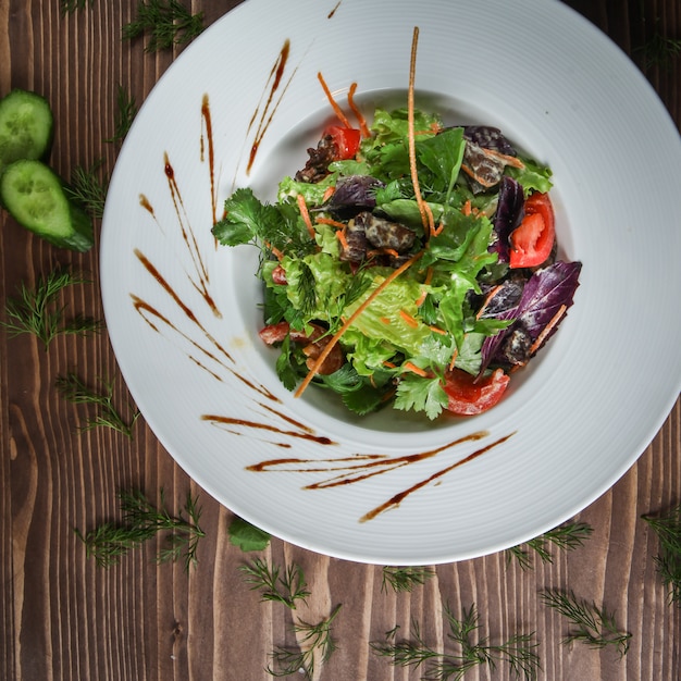 Free photo green salad in a plate with herbs, cucumber, tomato, carrot