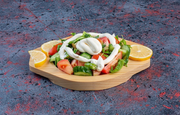 Green salad in a wooden platter with mayonnaise sauce. 