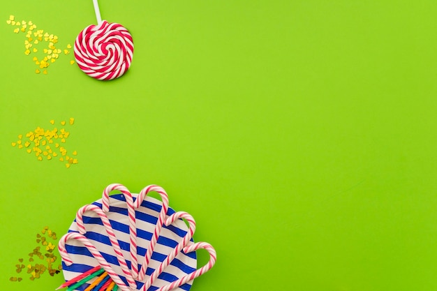 Free photo green surface with candy canes, lollipop and confetti