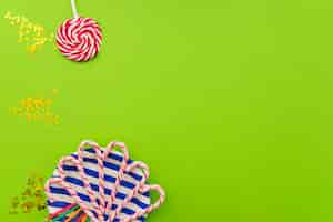 Free photo green surface with candy canes, lollipop and confetti