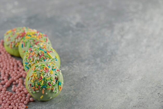 Free photo green sweet doughnuts with sprinkles.