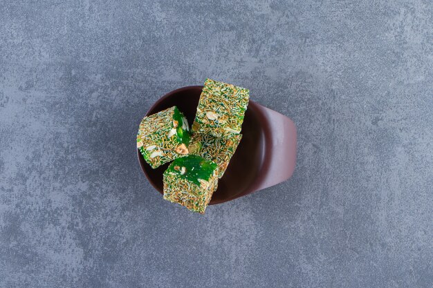 Green Turkish delights in a bowl, on the marble background.