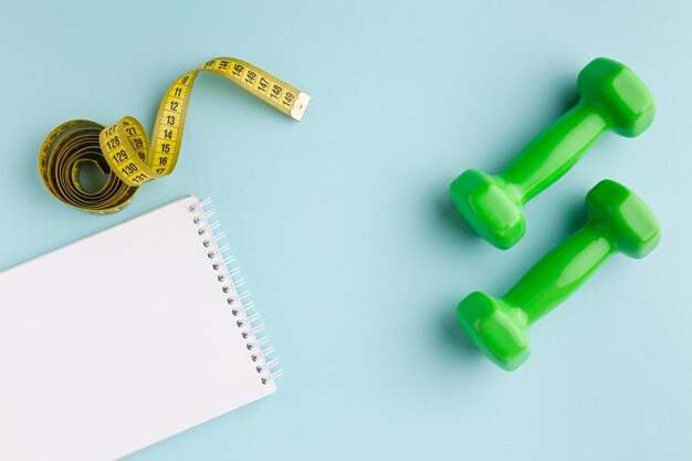 Green weights and notebook on blue background