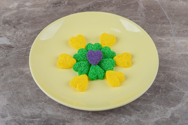 Green and yellow cookies on the plate, on the marble surface